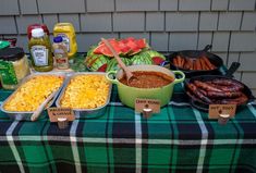 a table topped with lots of food and condiments on top of a checkered table cloth