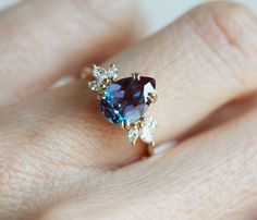 a woman's hand holding a ring with a blue and white stone in it