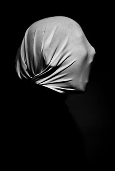 a black and white photo of a woman's head covered in a satin fabric