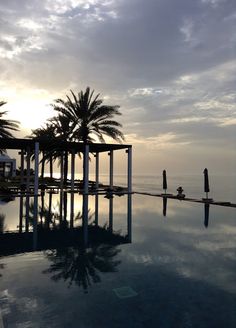 an empty swimming pool with palm trees and the ocean in the backgrouds