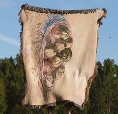 there is a large tapestry hanging from the side of a pole with trees in the background