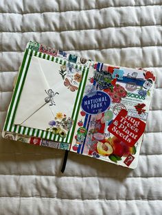 an open notebook on top of a bed covered in white sheets and papers with colorful designs