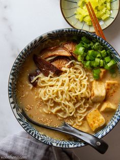 a bowl of ramen with tofu, noodles and scallions in it