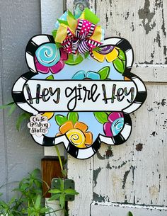 a sign that says hey girl hey hanging on the side of a door with flowers