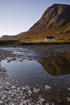 a small house sitting on top of a mountain next to a river