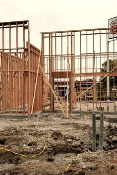 a construction site with wooden framing and signs on the building behind it that is under construction