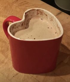 a heart shaped mug sitting on top of a wooden table