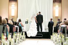 a bride and groom standing at the end of their wedding ceremony in front of an audience