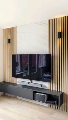 a flat screen tv sitting on top of a wooden shelf in front of a wall