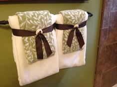 two towels hanging on a towel rack in a bathroom with green walls and tile flooring