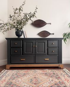 a black dresser with two wooden fish mounted on it's sides and a rug underneath