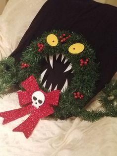 a black t - shirt with a green wreath and red bow on it's head