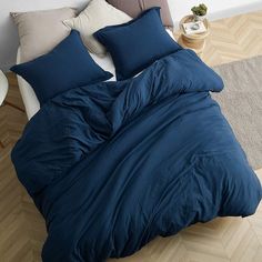 a bed with blue sheets and pillows on top of it in the middle of a room