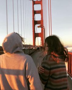 two people standing on the side of a bridge looking at the golden gate bridge in san francisco, california