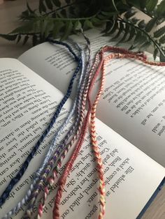 the book is open and there are three strands of yarn on top of an open book