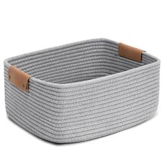 a grey basket with leather handles on the bottom and sides, sitting in front of a white background