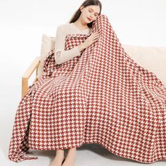 a woman sitting on a couch wrapped in a red and white checkerboard blanket