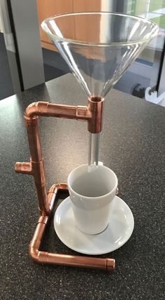 a cup and saucer sitting on top of a counter next to a metal faucet