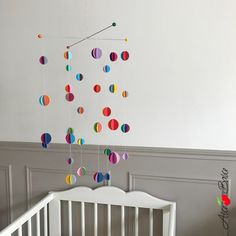 a baby crib with colorful paper balls hanging from it