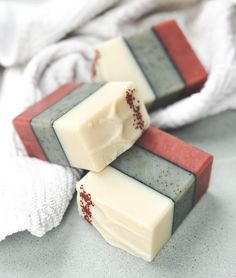 three bars of soap sitting on top of each other next to a white towel and cloth