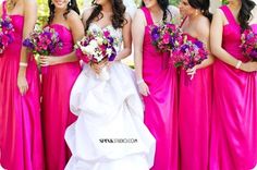 a group of women standing next to each other wearing pink dresses and holding bouquets