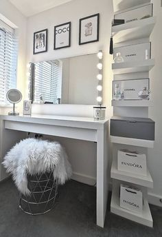 a white vanity with lights on it and a stool in front of the mirror next to it