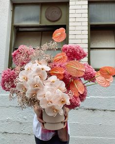 a person holding a bouquet of flowers in front of a building