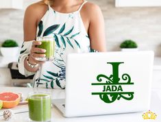 a woman holding a green smoothie in front of her laptop