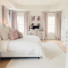 a white bed sitting in a bedroom on top of a hard wood floor next to two windows