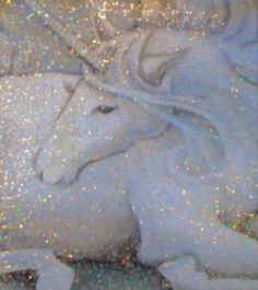 a white unicorn laying on top of a bed covered in glitter