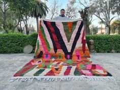 a man sitting on top of a multicolored rug