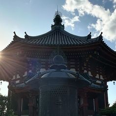 the sun shines brightly behind a tall building with an ornate roof and bell tower