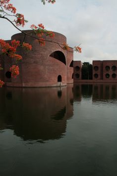 a large body of water next to a red brick building with arched doorways on each side