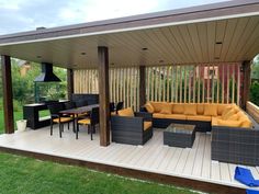 an outdoor living area with couches, tables and chairs on a deck in the grass