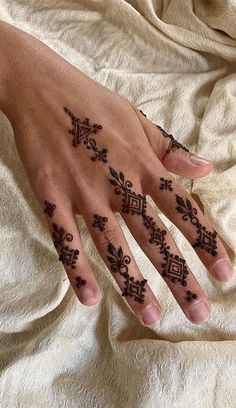 a woman's hand with henna tattoos on it