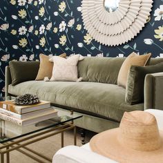 a living room with floral wallpaper and green couches in front of a round mirror