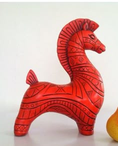 a red horse figurine next to a pear