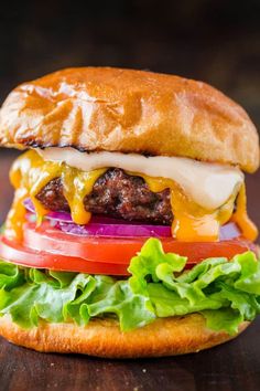 a cheeseburger with lettuce, tomato and onion on a wooden table