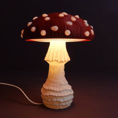 a mushroom shaped lamp is lit up on a dark surface with a cord attached to it