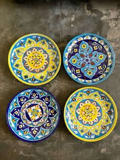 four colorful plates sitting on top of a cement floor