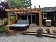 a hot tub sitting on top of a patio next to a wooden pergoline