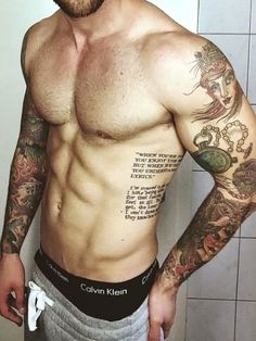 a shirtless man with tattoos on his chest standing in front of a tiled wall