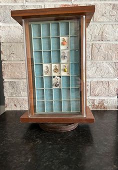 a wooden frame with glass tiles in it on a black counter top next to a brick wall