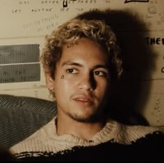 a close up of a person with tattoos on his face and hair in front of a wall