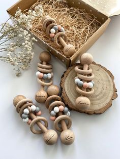 several wooden beads are arranged in front of a box with straw on the floor and flowers