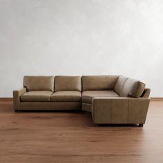 a brown leather couch sitting on top of a wooden floor next to a white wall