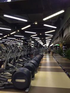 rows of stationary exercise bikes lined up in a large room with lights on the ceiling