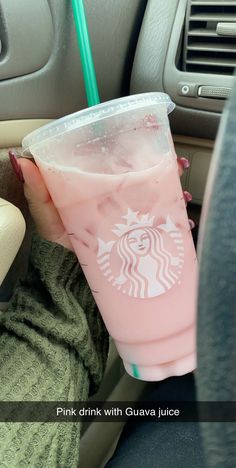 pink drink with guavaa juice sitting in the passenger seat of a car next to a woman's arm