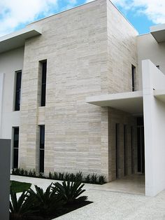 a large white building sitting next to a lush green tree on top of a sidewalk