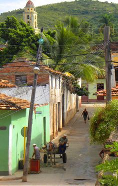 two people are sitting on a bench in the middle of an alleyway with mountains in the background